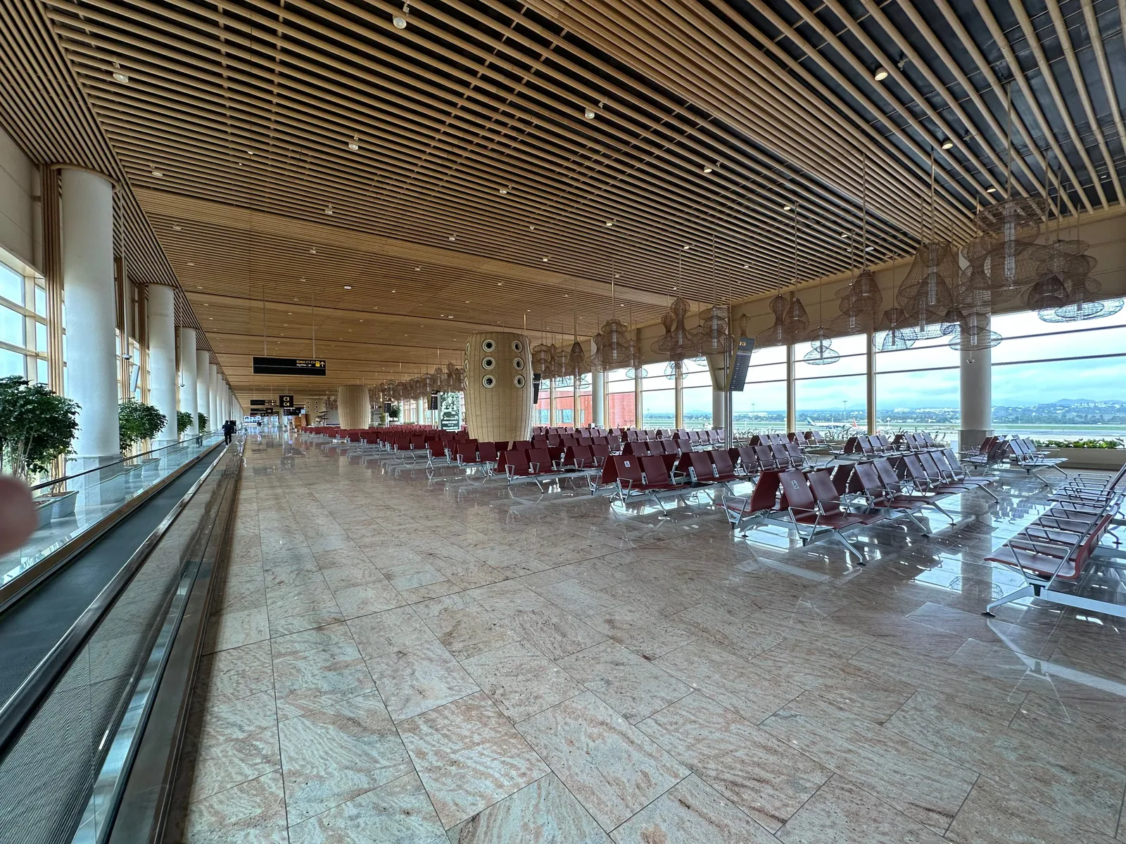 Inside Terminal 2 of Kempegowda International Airport, Bengaluru: rows of seats under a slatted wooden ceiling, the runway beyond the glass